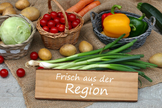 Regionales  Gem&uuml;se mit dem Text frisch aus der Region auf einem Holzschild.