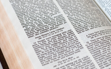Obraz premium Jesus blesses little children, biblical verses in an open Holy Bible Book. Christian biblical concept of love, humility, the kingdom of God, blessing, trust, and faith in the LORD. A closeup.