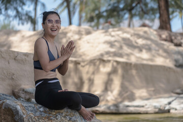 Fototapeta na wymiar Happy adult Asian woman doing yoga on the rock near beach, Yoga concept