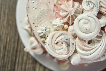 beautiful festive pink birthday cake decorated with marshmallows of different shapes and meringue. view from above