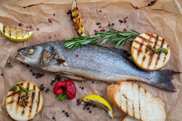 Appetizing sibas fish with greens and vegetables. On a wooden background.