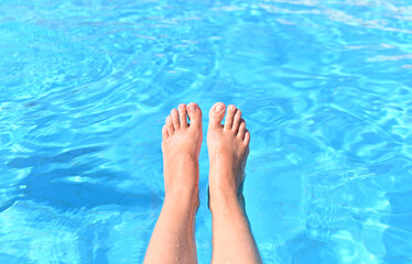 A woman with bare feet above the blue water of a swimming pool