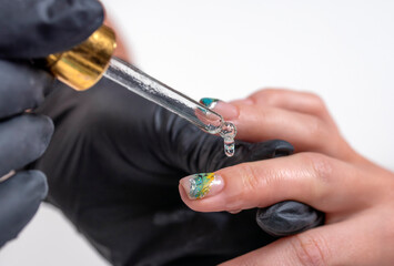 manicurist dripping anti-inflammatory oil on the cuticles of the client's fingers