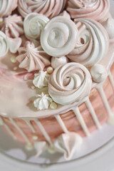 top view of beautiful pink marshmallows in different shapes that decorate a beautiful festive pink birthday cake with white chocolate drips around the edges