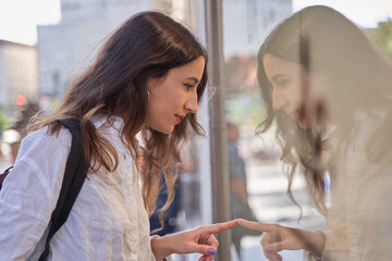 Close-up portrait of a young woman looking in a shop window