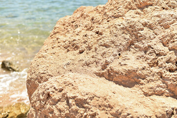 Background for cosmetics on the beach with sand. The podium is made of natural stone. A mock-up of a pedestal in the sunlight with a view of the sea.