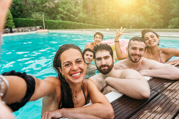 Smartphone self-portrait of a group of friends at the hotel outdoor pool during their summer vacation - Young people take a souvenir selfie photo in swimsuits having fun together in a relaxing moment - 519396510
