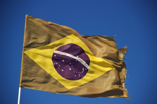 Bandeira do Brasil flamulando com céu azul ao fundo - Brazil flag waving with blue sky in the background