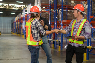 Group of young worker wearing helmet checking inventory and discussing in modern warehouse.