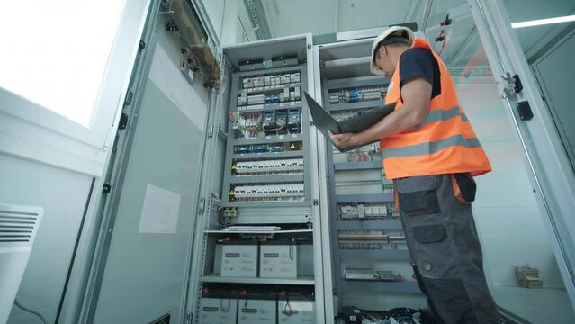 Electrical engineer working check the electric current voltage and overload at front of load center cabinet or consumer unit for maintenance in main power distribution system room.