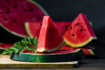 Delicious watermelon  outdoors wooden  table, GREEN  natural background sunny day, Heap,  Fresh ripe red, leaf, summer sunny garden juice drink organic sweet fruit, vegan food Tasty sliced board plate