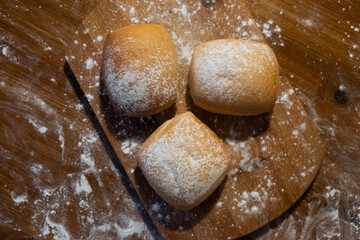 Three buns sprinkled with flour on a wooden board. Buns on the table. Bakery products.