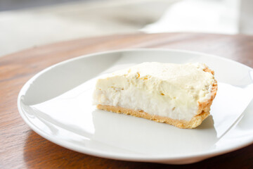 Clear Coconut Cream Pie in the dish on the wood table without anything topping on it. Shooting in the sunlight.