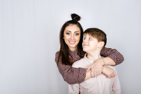 Parenting Teen Boys, Raising A Teen. Studio Portrait Of Happy Teen Boy Hugging His Mom