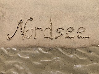 Fototapeta premium Schrift Nordsee am Strand bei ablaufendem Wasser / Ebbe