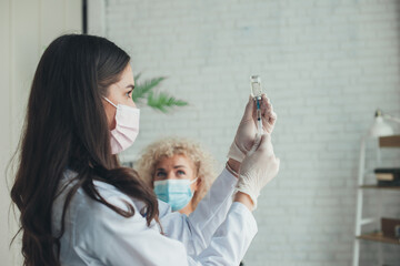 Nurse drawing medication out of vial before giving injection to patient, in the hospital. Coronavirus vaccination. Coronavirus prevention. Pandemic prevention. - obrazy, fototapety, plakaty