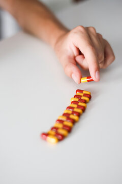 Close-up of a person lining up a row of pills on a table
