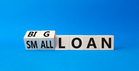 Big loan and Small loan symbol. Turned cubes with words Small loan and Big loan. Beautiful blue background. Busines concept. Copy space