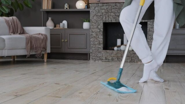 Close-up female legs graceful woman dancing rehearsing choreography while cleaning active energetic girl washes floor with mop in living room dances to music performs professional dance move at home