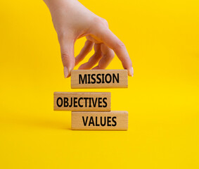 Mission Objectives Values symbol. Concept words Mission Objectives Values on wooden blocks. Beautiful yellow background. Businessman hand. Business and Mission Objectives Values concept. Copy space