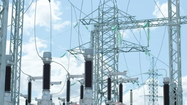 Motion past glass insulators on supports and cable bus pipes in switchyard of contemporary substation under clear blue sky