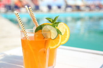 Refreshing cocktail in glasses near outdoor swimming pool on sunny day