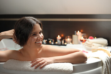 Obraz na płótnie Canvas Happy beautiful woman taking bath indoors. Romantic atmosphere