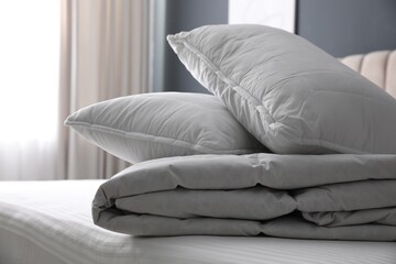 Fototapeta na wymiar Soft folded blanket and pillows on bed indoors, closeup