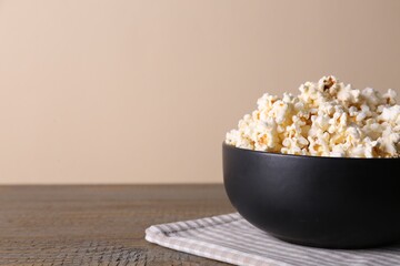 Delicious popcorn in bowl on wooden table. Space for text