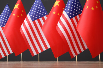 USA and China flags on wooden table against dark background. International relations