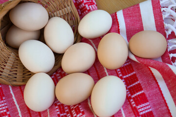 Overturned wicker basket with fresh raw eggs on table