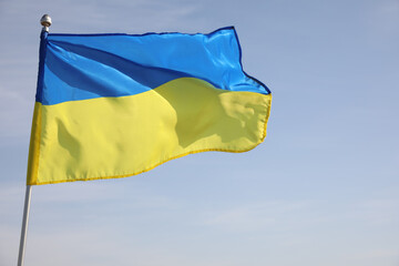 National flag of Ukraine against blue sky, closeup