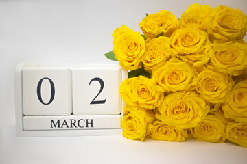 Wooden calendar March 2 and yellow roses on a white background. The concept of a holiday, a plan, an important event . High quality photo 