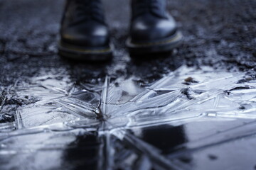 Close up of a frozen puddle with a person standing behind it