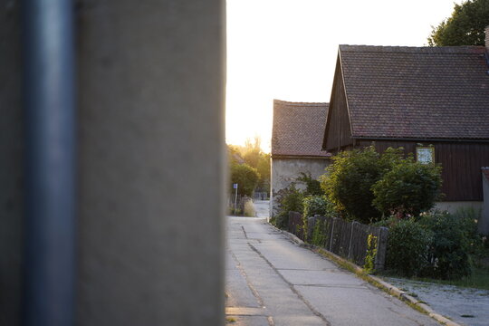 Split image of a grey wall and a sunny town neighbourhood at sunset