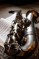 Naklejka premium Silbernes Alt-Saxofon, liegend auf einem offenen Notenheft