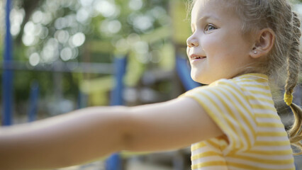 Cute little girl plays on the playground. Child girl playing on the playground in the city park