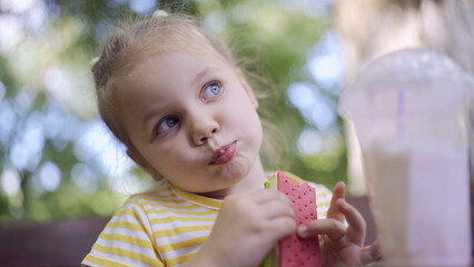 Closeup of cute little girl eats ice cream. Close-up of child girl sitting on park bench and eating icecream.