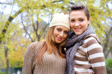 Two beautiful girls having fun in the park on colorful autumn day