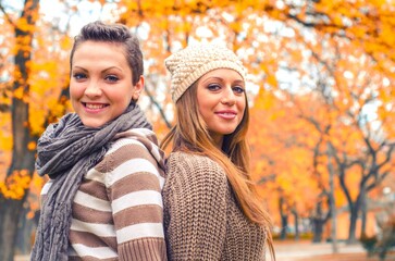 Two beautiful girls having fun in the park on colorful autumn day