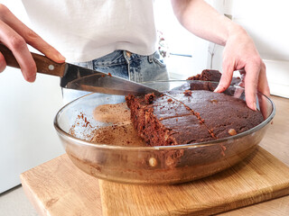 fresh vegan bread round in a glass form on an evil housewife girl cuts in the kitchen