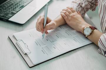 Close-up of businesswoman hand making notes in calendar diary on desk. Female hand planning on calendar
