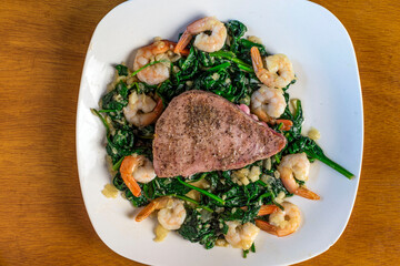 season tuna steak  with spinach onions and shrimp