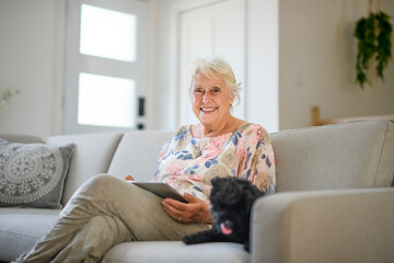 cute senior woman with poodle on the living room using a tablet