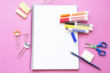different colored felt-tip pens and other stationery on blank page of notebook