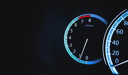 Round per minute (RPM) gauge illuminated on a car dashboard with copy space