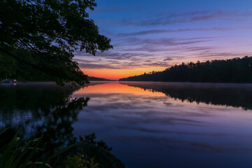Pemaquid River in Maine is calm and vibrant with deep purple hues on a summer morning at sunrise