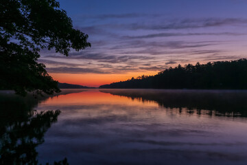 Fototapeta na wymiar Pemaquid River in Maine is calm and vibrant with deep purple hues on a summer morning at sunrise