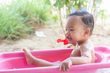 Happy children boy bath in plastic basin  in nature and play in the water. outdoor water treatments. space for text. High quality photo