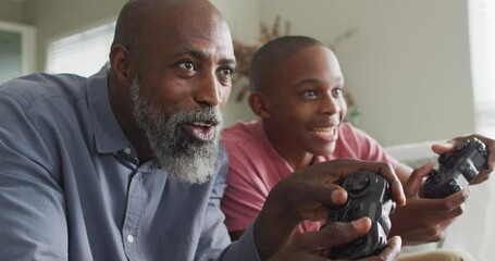 Video of happy african american father and son playing video games - Powered by Adobe